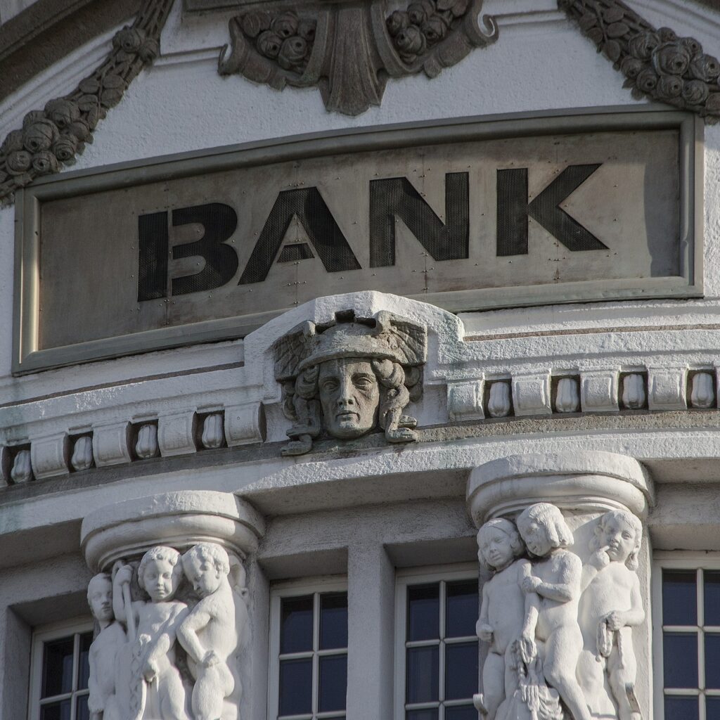 The outside of a bank has statues. 