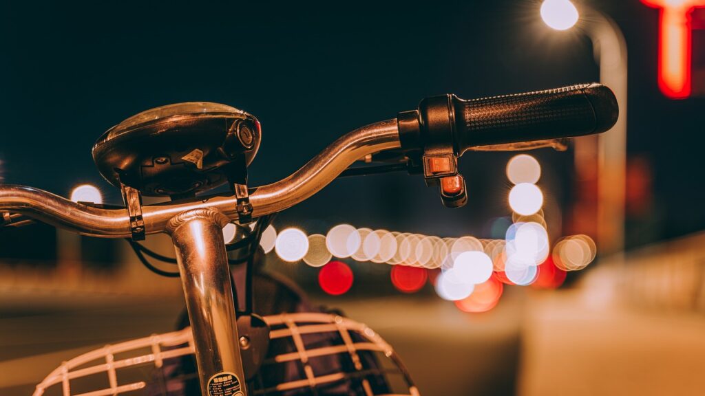 A close-up of bicycle handlebars at night. 