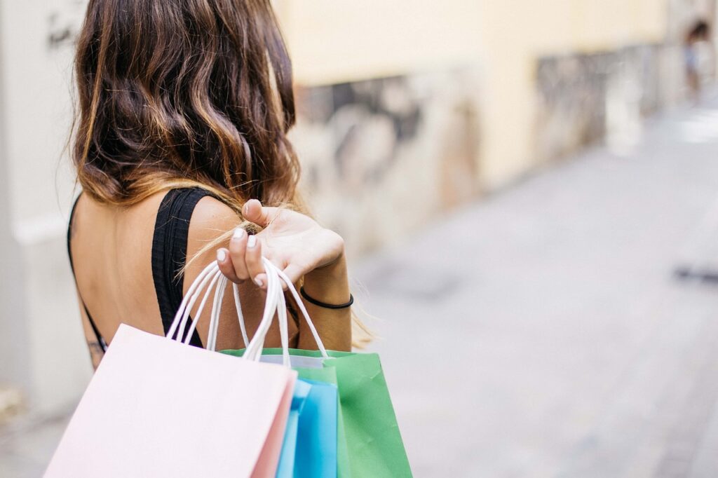 A woman walks down the street holding shopping bags. 