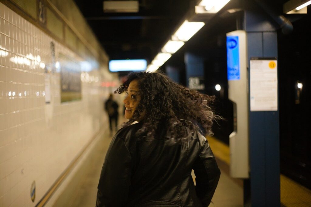 A smiling woman walks through a subway to save on transportation. 