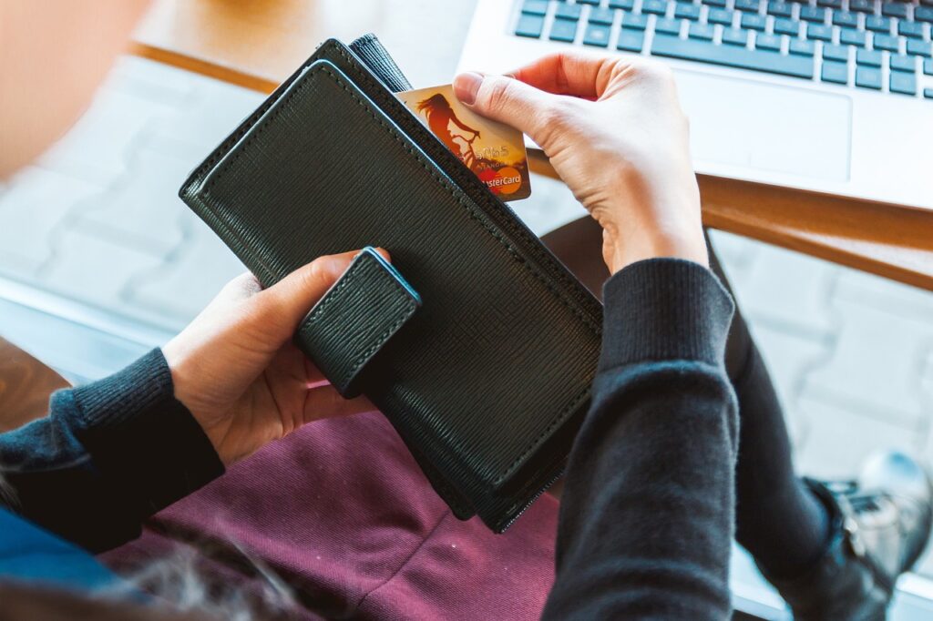 A woman takes out a credit card from her purse as she discusses debt snowfall vs avalanche. 