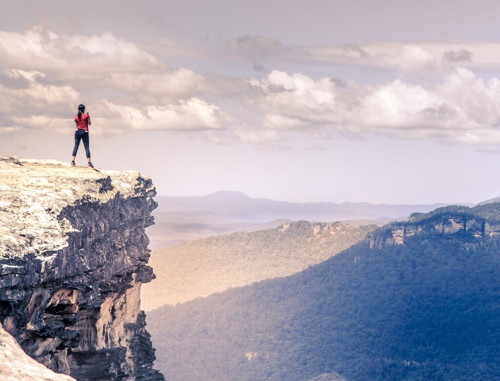 A woman takes a picture of a scenic view from a mountain